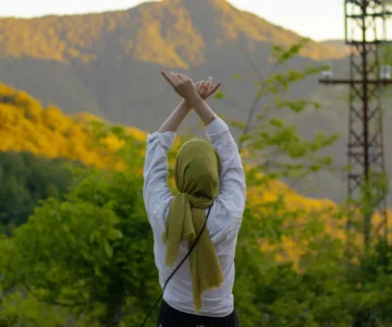 A woman with her arms raised in self-acceptance outdoors