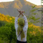 A woman with her arms raised in self-acceptance outdoors